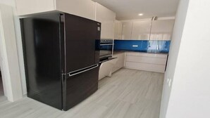 A modern kitchen with white cabinets, a black refrigerator, and a blue backsplash. - Luxury apartment Ani II  - Two Bedroom Apartment with Terrace (Sutivan)