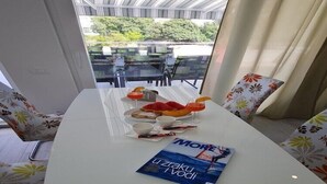 A dining area with a white table, floral chairs, and a magazine. - Luxury apartment Ani II  - Two Bedroom Apartment with Terrace (Sutivan)