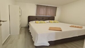 A single bed with a headboard, a window with curtains, a white door, and a light-colored floor. - Luxury apartment Ani II  - Two Bedroom Apartment with Terrace (Sutivan)