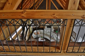 A wooden ceiling with a truss structure, a white sofa with cushions, and a small round table with a flower vase.