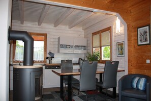 A kitchen with a wood stove, dining table, chairs, and a window with blinds.