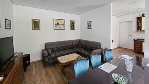 A living room with a sectional sofa, a TV, a small table, and framed pictures on the wall. - Apartment Gracac - Two Bedroom Apartment with Terrace (Gracac)