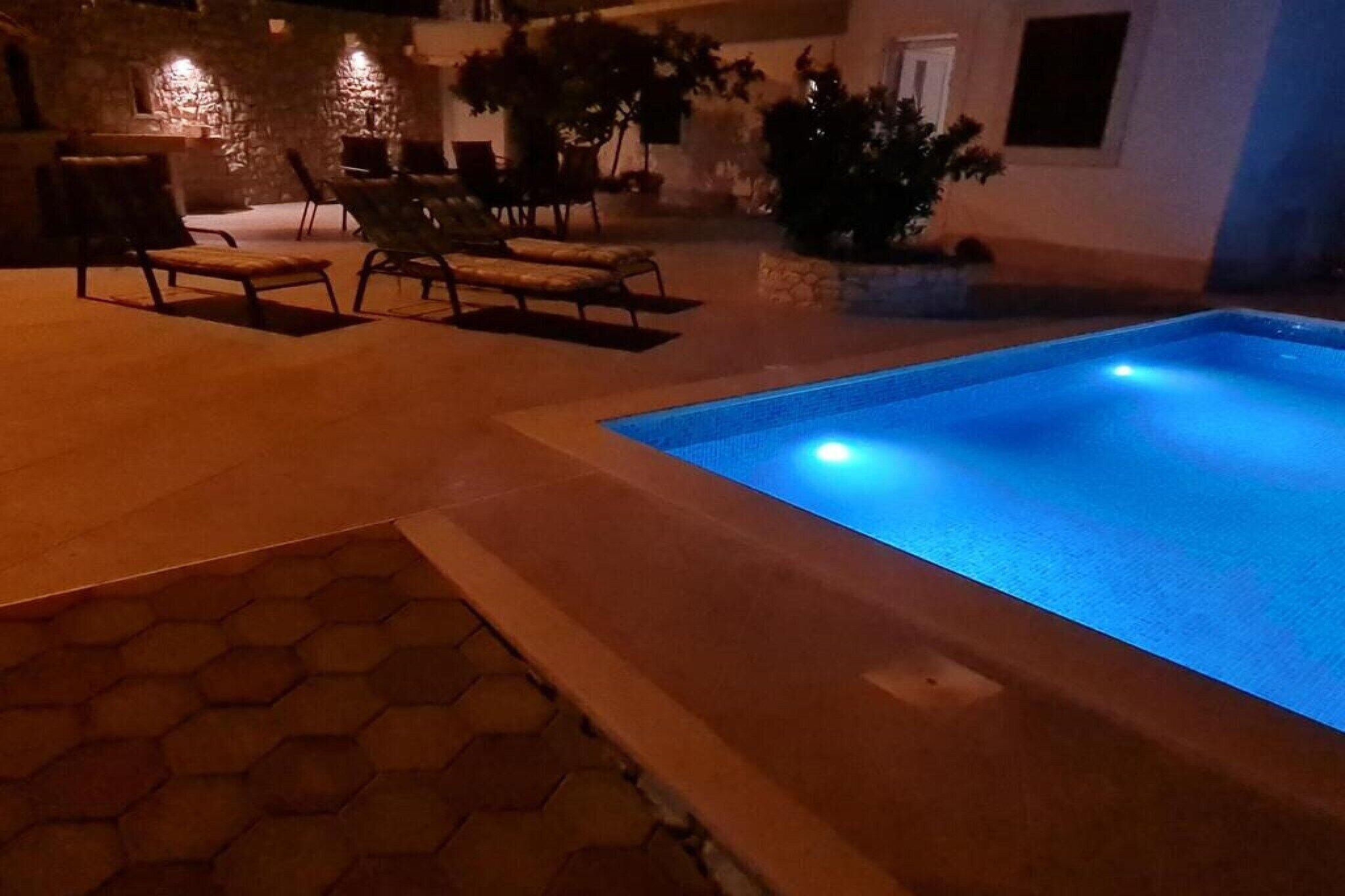 Un espace extérieur avec une piscine, des chaises longues et un mur en pierre.