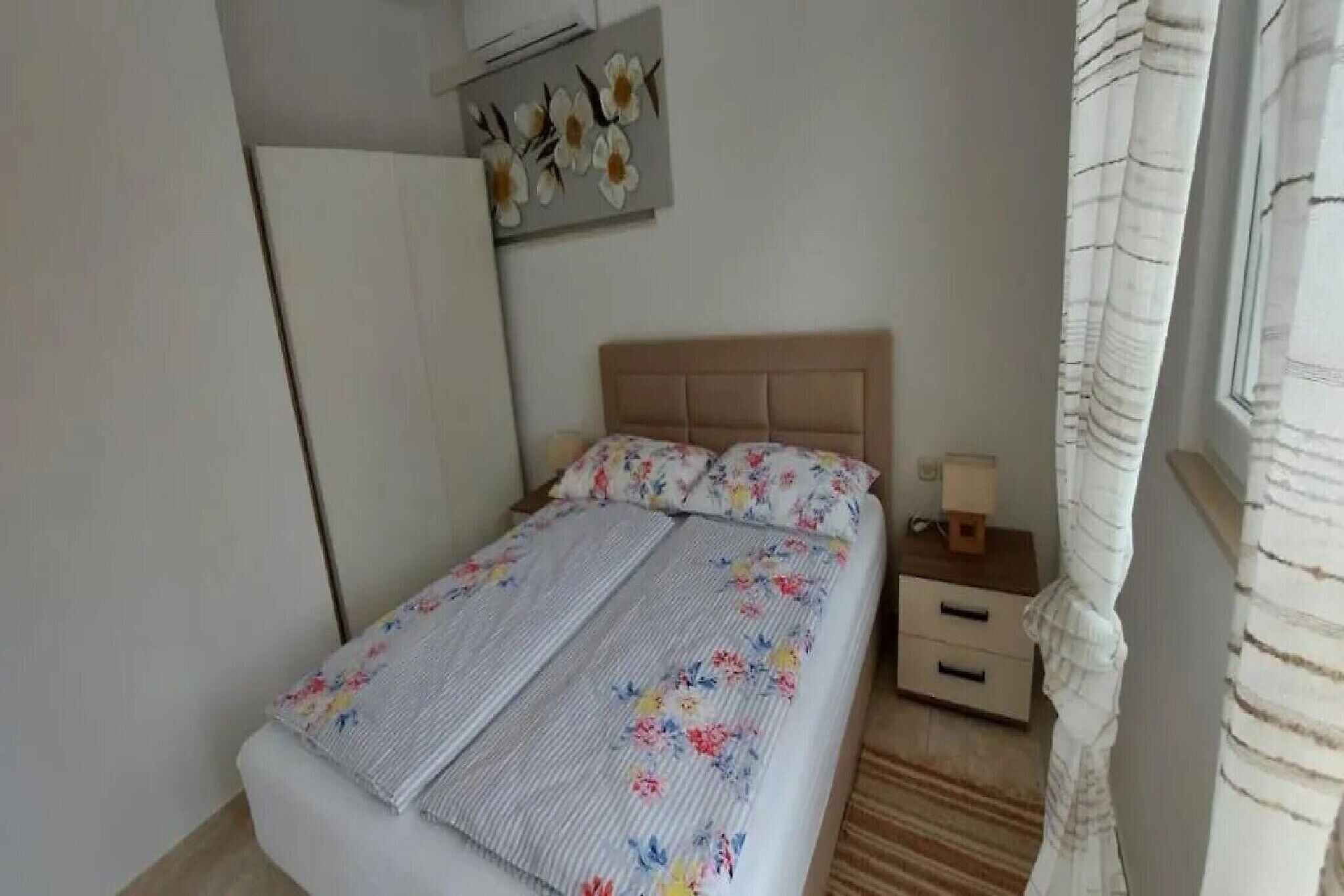 Een slaapkamer met een bed, nachtkastje, lamp, kledingkast en een decoratie aan de muur.
