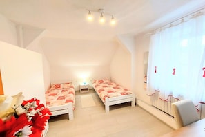Une chambre avec deux lits simples, un bureau et une chaise.