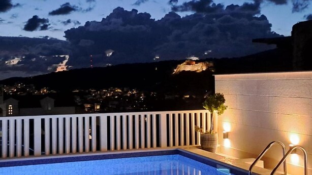 Une piscine sur le toit offrant une vue sur le paysage urbain au crépuscule.