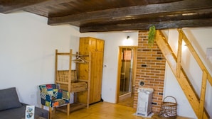 A cozy living room with a wooden chair, a sofa, a wooden cabinet, and a brick wall.