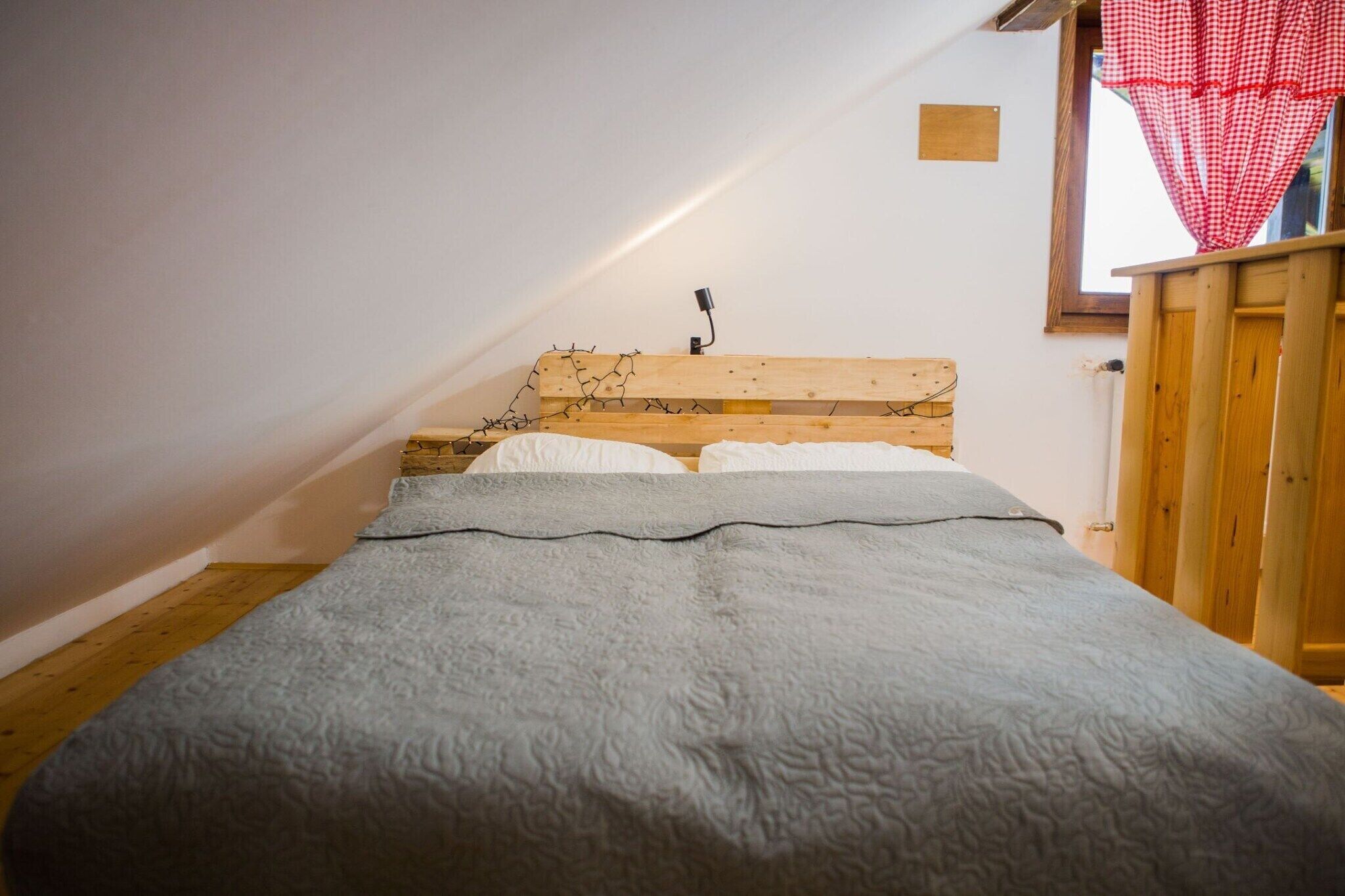 Una cama individual con cabecera de madera y una colcha gris con textura.