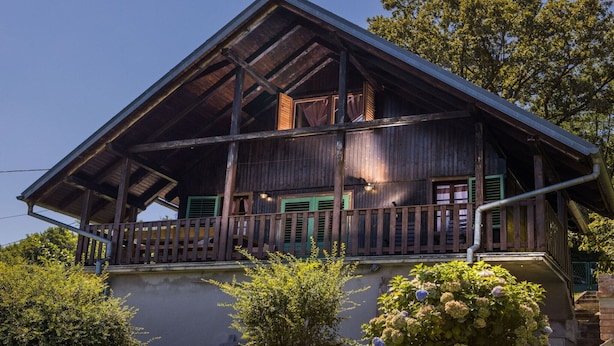 A wooden house with a balcony, a staircase, and a garden.