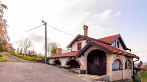 Ein zweistöckiges Haus mit rotem Ziegeldach, Schornstein und einer Fassade aus Stein.
