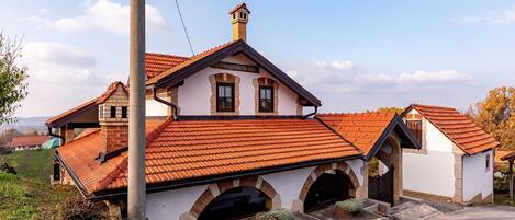 A traditional building with a tiled roof, arched entrance, and a chimney.