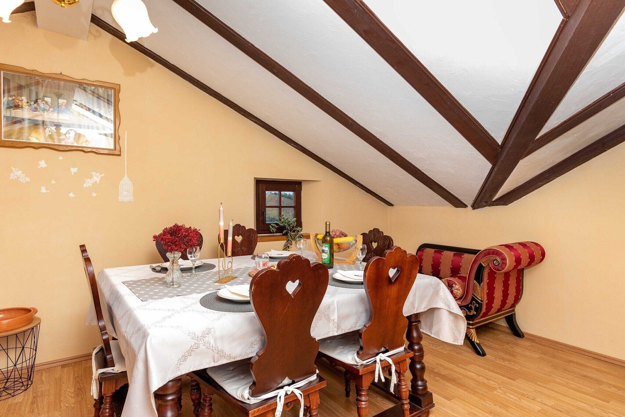 Un coin repas avec une table dressée pour quatre personnes, des chaises en bois, un canapé à rayures rouges et un tableau accroché au mur.