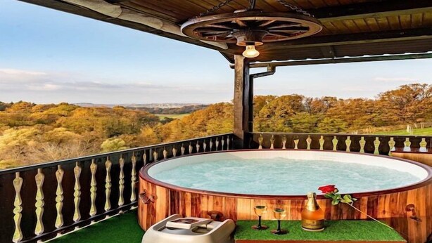 Ein hölzernes Whirlpool mit Blick auf eine bewaldete Landschaft.