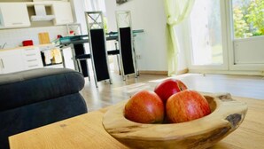 Eine Holzwasserlie mit Äpfeln auf einem Tisch in einer modernen Küche mit weißen Schränken und einem Essbereich.