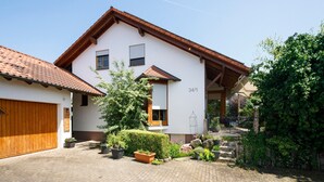 A two-story house with a tiled roof, a wooden garage door, and a number '34/1' on the building.