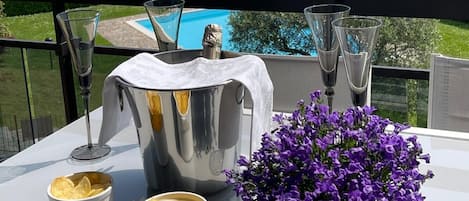 Una mesa dispuesta con una jofaina de plata, dos vasos y dos cuencos de totopos, junto a una maceta con flores moradas.