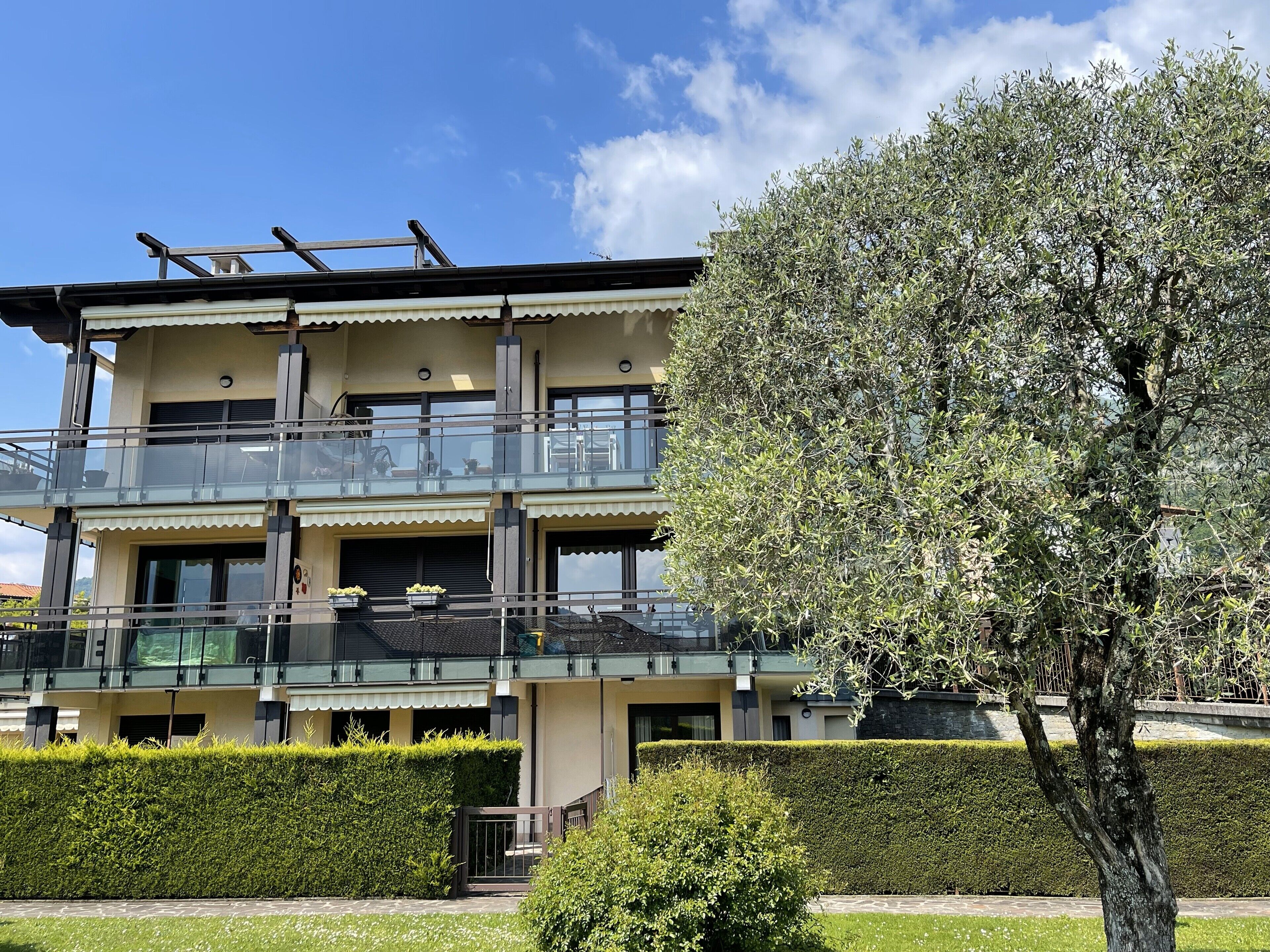 Un edificio a più piani con balconi, una scala e un giardino curato.
