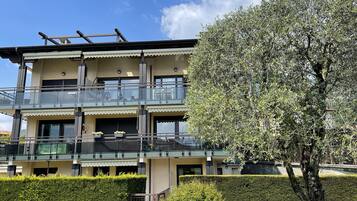 Un edificio a più piani con balconi, una scala e un giardino curato.