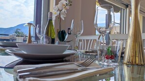 A dining table set with plates, cutlery, and wine glasses, with a bottle of wine and flowers on the table.