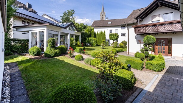 Zona residencial com jardins bem cuidados, o topo de uma igreja e diversos tipos de casas.