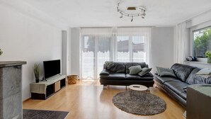 Una sala de estar moderna con una televisión de pantalla plana, dos sofás, una mesa de centro y una chimenea.