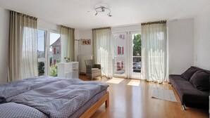 Un dormitorio con cama, sofá, silla y ventana con cortinas.