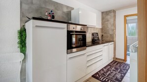 Una cocina moderna con armarios blancos, electrodomésticos de acero inoxidable y una encimera negra.