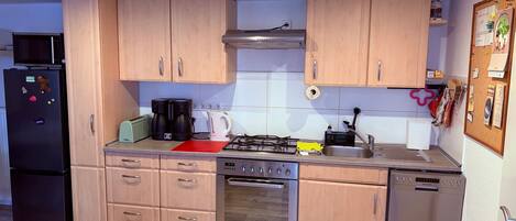 A modern kitchen with wooden cabinets, a black refrigerator, a stove, and a dishwasher.