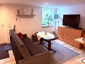 Una sala de estar con un sofá, una mesa de comedor, un televisor y un aparador.