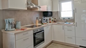 A modern kitchen with white cabinets, a built-in oven, a microwave, and a sink.