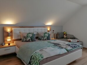 A modern bedroom with a large bed, bedside tables, a nightstand, and a decorative pillow. - Holiday Home 'Hexenpfad' with Private Terrace, Private Garden and Wi-Fi (Hasselfelde)