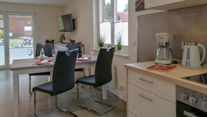 Eine moderne Küche mit Essbereich, inklusive Fernseher, Kaffeemaschine und Blick ins Freie.