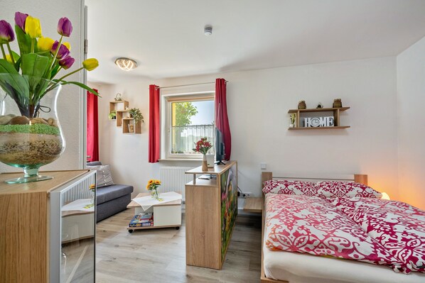 A modern room with a bed, a desk, a sofa, a window with curtains, and a shelf with a 'HOME' sign.