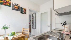 Una cocina compacta con un lavamanos, una mesa de comedor con sillas y un espejo.