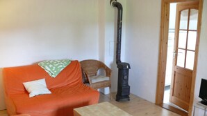 Sala de estar com sofá, mesa pequena, cadeira, aspirador de pó e porta de madeira.