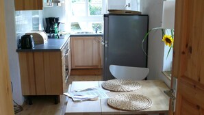 Uma cozinha compacta com armários de madeira, geladeira, pia e janela com vista para o verde.