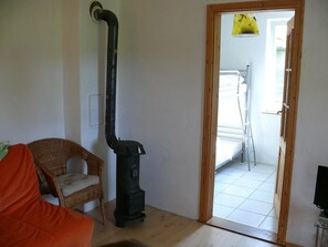 Une pièce où se trouvent un aspirateur noir, une chaise en osier et une porte en bois donnant sur une buanderie.
