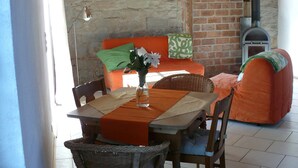 Un coin repas avec une table dressée pour deux personnes, une chaise en osier, un canapé et un mur en briques.