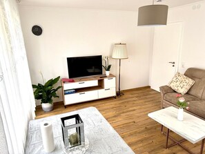 A living room with a TV, sofa, coffee table, and a lamp.