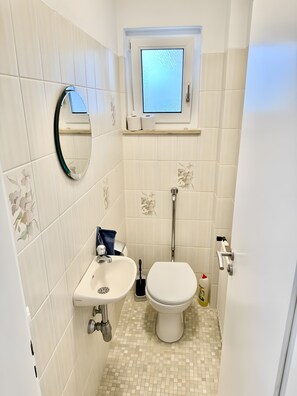 Een kleine badkamer met toilet, wastafel en raam.