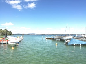 A marina with boats docked, calm water, and a clear sky.