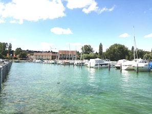Un puerto deportivo con barcos amarrados, cielo despejado y edificios al fondo.