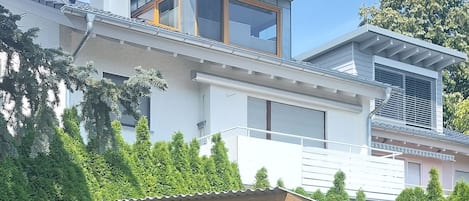 Ein modernes, zweistöckiges Haus mit überdachter Terrasse.