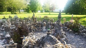 Een tuin met stenen sculpturen en een vijver.