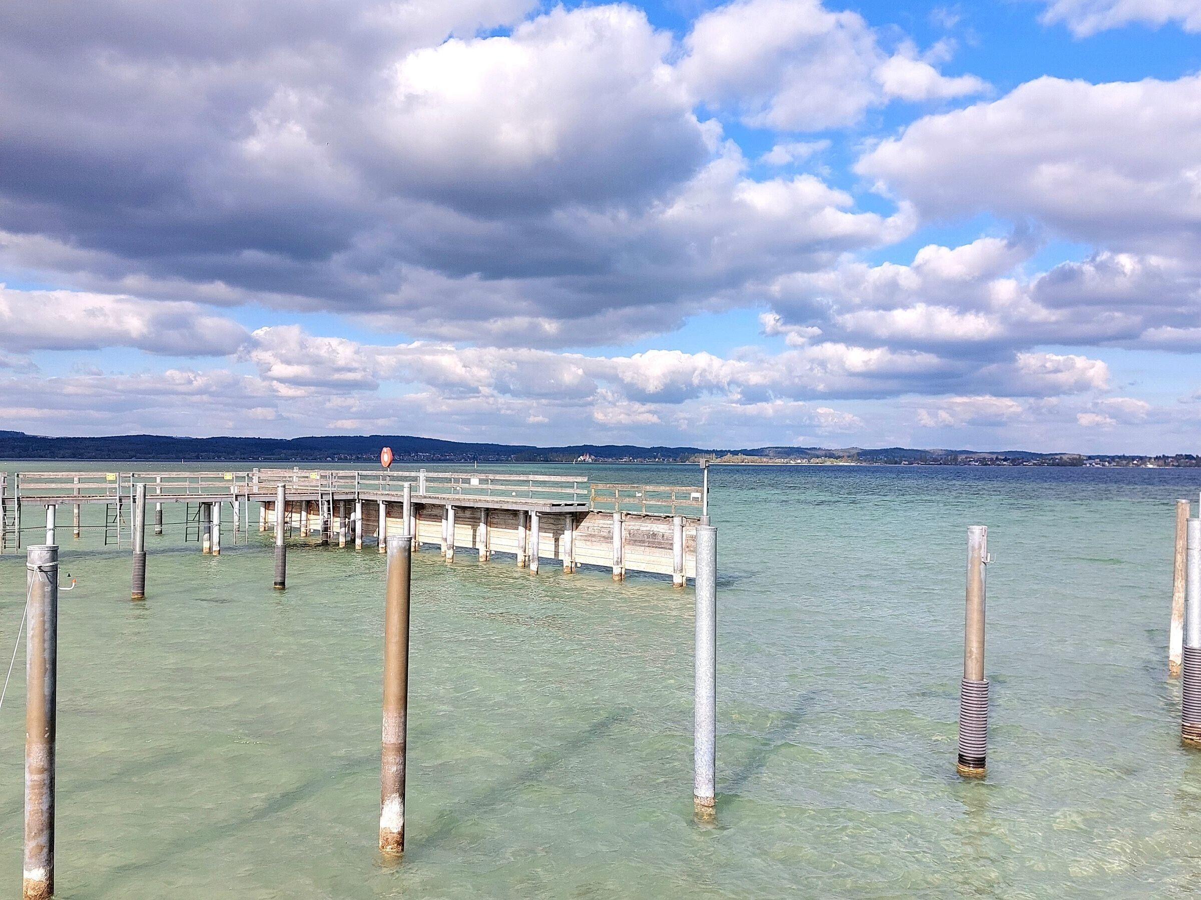 Un muelle se adentra en aguas claras bajo un cielo nublado.