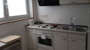 A compact kitchen with a window, a microwave, a sink, and a small oven. - Apartment 'Am Finkenweg Ground Floor' with Shared Terrace and Wi-Fi (Bestwig)