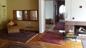 A living room with a sofa, a small table, and a fireplace. There are multiple rugs on the floor.