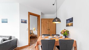 Un coin repas avec une table dressée pour quatre personnes, un canapé, un meuble en bois et une suspension.