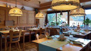 Ravintola, jossa on puusisustus, useita ruokapöytiä ja katosta roikkuvia lamppuja.