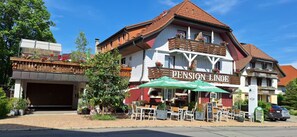 Un edificio con un cartello 'Pension Linz' e posti a sedere all'aperto ombreggiati da ombrelloni.